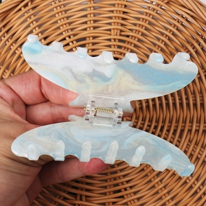 Detail of gradient blue butterfly hair claw with gold glitter held over a woven basket