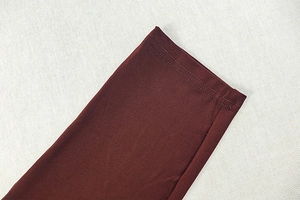 Gros plan détaillé du tissu brun rouge foncé avec doubles coutures précises et ourlets nets