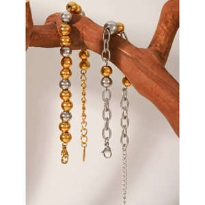 Bracciali a perline bicolore oro e argento in acciaio inossidabile su un ramo di legno
