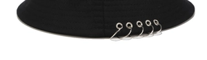 Détail d'un bob noir avec cinq anneaux métalliques argentés au style punk de rue