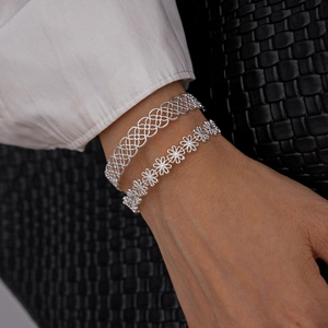 Detailed view of silver cuff bracelet set with hollow grid and daisy flower designs