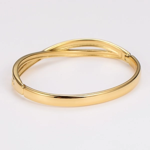 Detailed view of golden twisted knot bangle with polished finish and hinge clasp closure