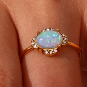 Close-up of 18K gold plated adjustable ring featuring an oval opal and crystal halo