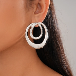 Close-up of double circular silver earrings with molten texture on a female model
