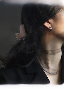 Close-up of model wearing gold C-shaped hoop earrings with square zircon stone
