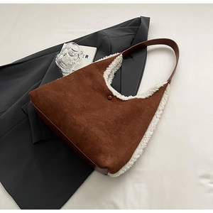 Detailed view of a brown faux suede tote bag featuring white faux shearling trim and button