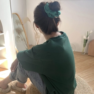 Detail of a green satin scrunchie with pearl accents on a matching cotton t-shirt