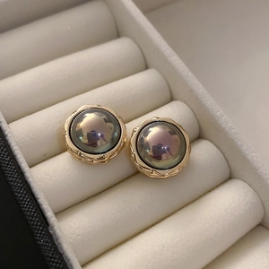 Vue macro de boucles d'oreilles dorées vintage avec centre gris sur velours