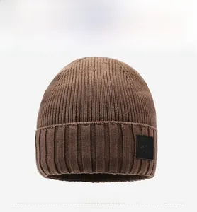 Detailed front view of dark brown knitted beanie with vertical ribbed texture and leather patch