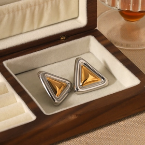 Minimalist gold and silver two-tone triangle stud earrings in a wooden jewelry box
