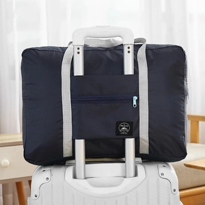 Large blue travel storage bag attached to suitcase handle for easy luggage transport