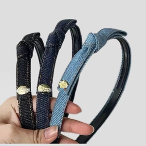 Detail of three denim knotted headbands in black and blue with gold button accents