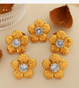 Detail of vintage flower stud earrings with gold base, white gems and pearls