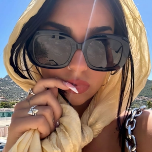 Chic black square frame sunglasses worn with yellow silk scarf in a sunny coastal setting