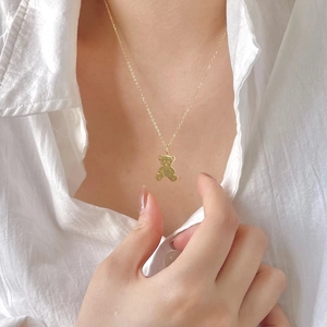 Detailed view of a gold teddy bear pendant with cutout heart on a delicate chain
