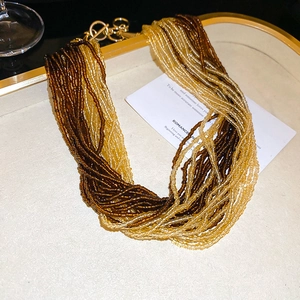Dettaglio della collana bohémien multifilo in perline con chiusura a barra in oro lucido
