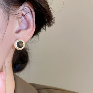 Macro detail of retro golden geometric stud earring with round brown stone inlay