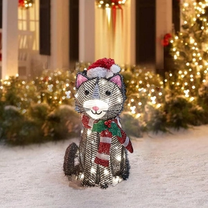 Close-up of glowing metal wire sitting cat outdoor Christmas decor on snowy garden ground