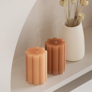 Vue détaillée de bougies colonnes géométriques nervurées avec textures de pétales sur socle
