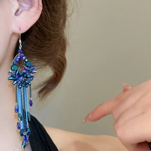 Detailed view of long beaded tassel earrings with sparkling blue crystals on model