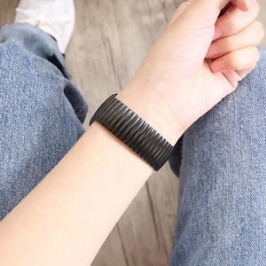 Black striped elastic stainless steel watch band worn by a model in a lifestyle setting