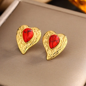 Macro view of gold heart stud earrings with textured twist edge and red stone inlay