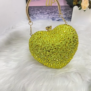 Close-up of heart-shaped evening clutch with yellow rhinestones and gold ring handle