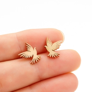 Close-up of small golden bird stud earrings held by hand to show compact size