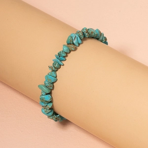 Detail of bohemian turquoise stone bracelet with irregular beads on a beige prop