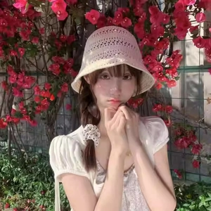 Detail of beige hollow crochet bucket hat worn by model against a floral background