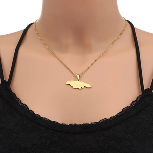 Close-up of a gold Jamaica map pendant necklace with letter engraving on black lace