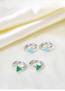 Macro shot of silver hoops with blue and green triangle-cut zircons on silk background