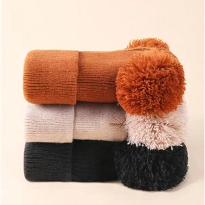 Detailed knit texture and soft pom-poms on caramel, cream, and black winter hats