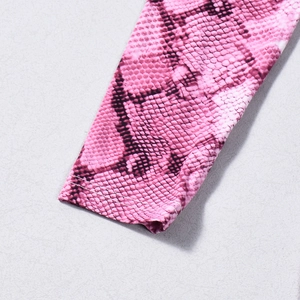 Détail du tissu à imprimé serpent rose avec coutures professionnelles sur les poignets