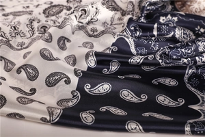 Close-up of white and navy paisley silk scarf with glossy texture and intricate patterns