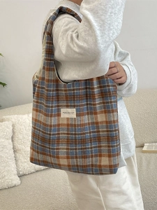 Vintage plaid tote bag in blue and brown checkered wool worn by model in a cozy room