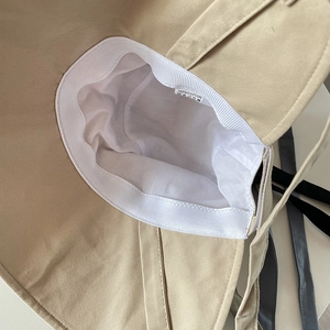 Inside view of beige cotton sun hat showing 100% cotton label and white fabric lining