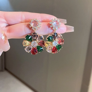 Detail of vintage gold flower earrings with colorful zircons worn by a model