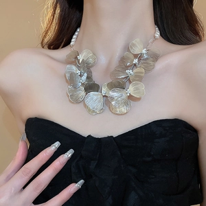 Detailed view of hollow metal flower petals and white pearls on the necklace