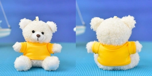 Front and back view of a plush white teddy bear pendant wearing a yellow t-shirt