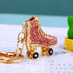 Detailed close-up of a gold-plated roller skate keychain with pink rhinestones
