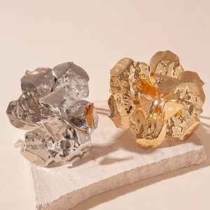 Artistic hammered metal flower open bracelets in gold and silver finish on stone pedestals