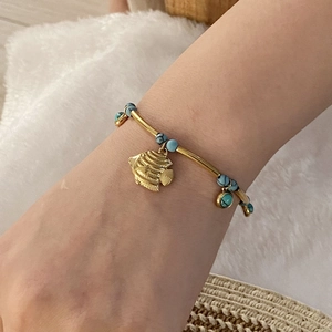 Golden ocean theme bracelet with turquoise beads and fish charm on woman's wrist