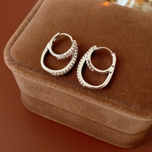 Detailed view of silver double-hoop earrings with cubic zirconia on a brown velvet box