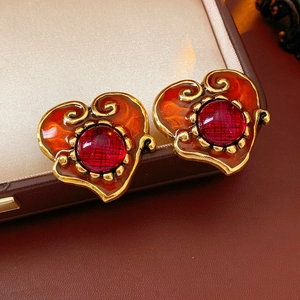 Detail of vintage heart earrings with gold alloy frame and red enamel on leather