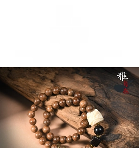 Macro detail of sandalwood beads with intricate white relief charm on a wooden base