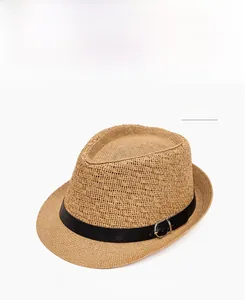 Detail of khaki straw fedora hat featuring a black ribbon band and metal buckle
