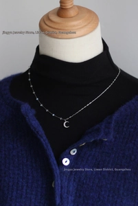 Detail of silver crescent moon pendant with crystal beads on a delicate chain