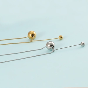 Close-up of gold and silver stainless steel ball necklaces with glossy finish and tassels