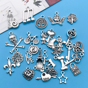 Collection of various Tibetan silver charms for DIY jewelry making on blue background